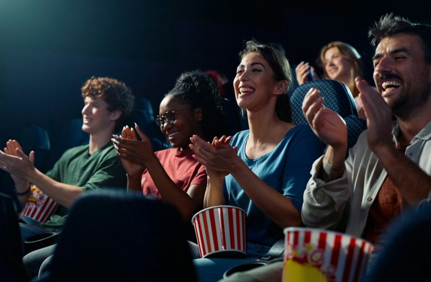 Happy spectators applauding after movie projection in cinema.